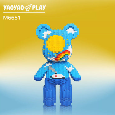 Blue Brick Bear toy (Model M6651) with yellow sun face, rainbow arc, and cloud-patterned ears. Caption: Inspire imagination with this celestial-themed Brick Bear building blocks toy—crafted for playful assembly and display.