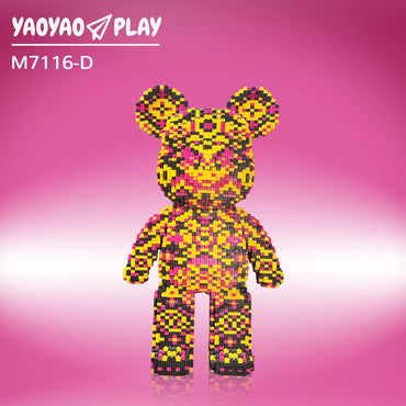 A Kumamon-inspired Brick Bear toy with yellow, pink, and black pixel blocks, model "M7116-D," on a gradient pink backdrop